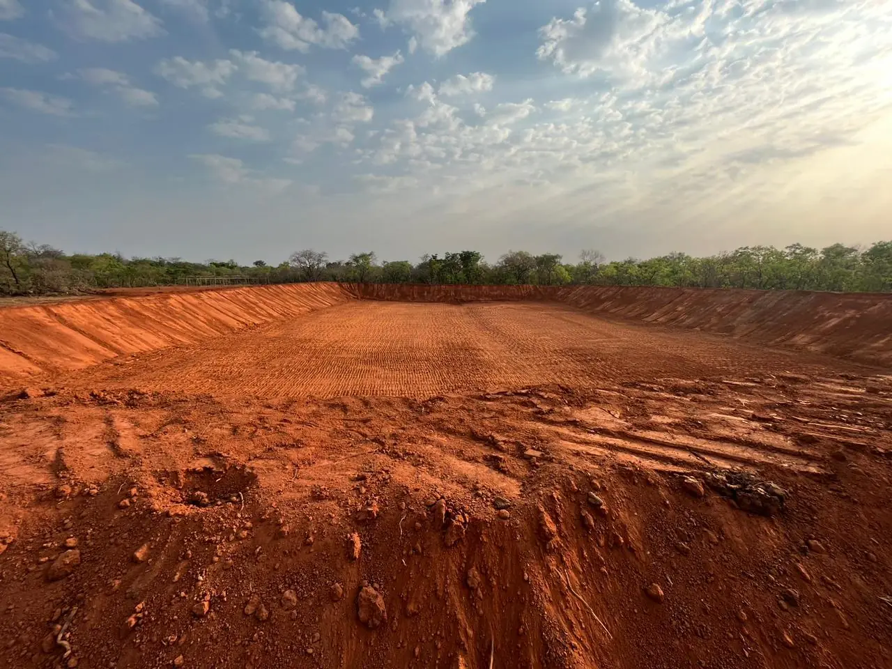 Cleared red earth at a Sudanese site under an open sky